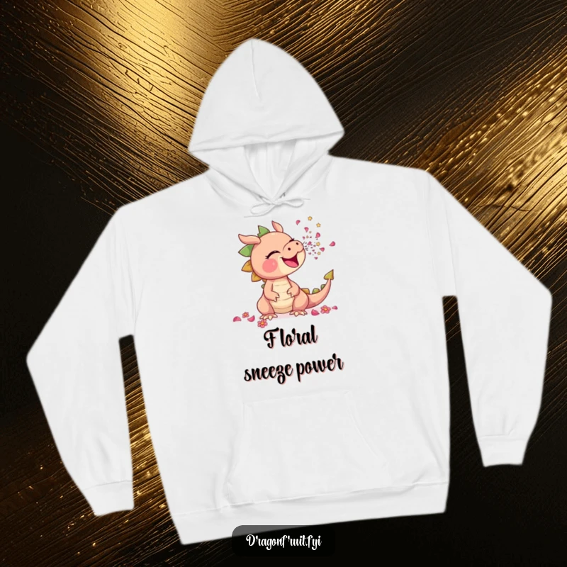 Funny hoodie illustrates a dragonfruit comically sneezing a shower of tiny flower petals, offering cozy floral humor.
