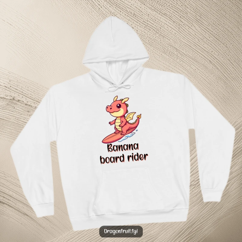 Funny hoodie depicting a happy dragonfruit character surfing a banana slice surfboard, perfect for cozy, tropical cheer.